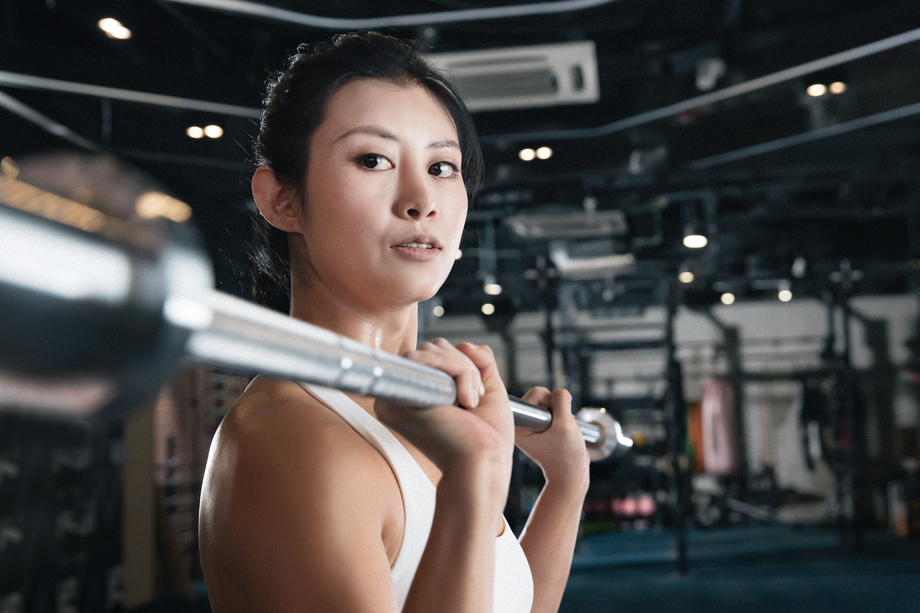 年轻女子在健身房练习抗杠铃