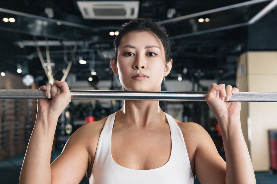 年轻女子在健身房练习抗杠铃照片