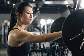 健身房里年轻女子趴在杠铃上休息