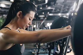 健身房里年轻女子趴在杠铃上休息