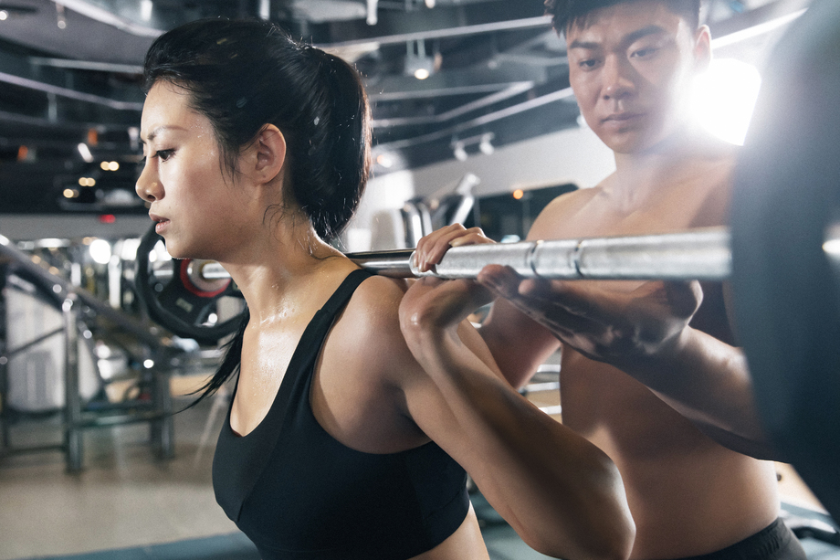 年轻女子在教练指导下举杠铃 年轻女子在教练指导下举杠铃