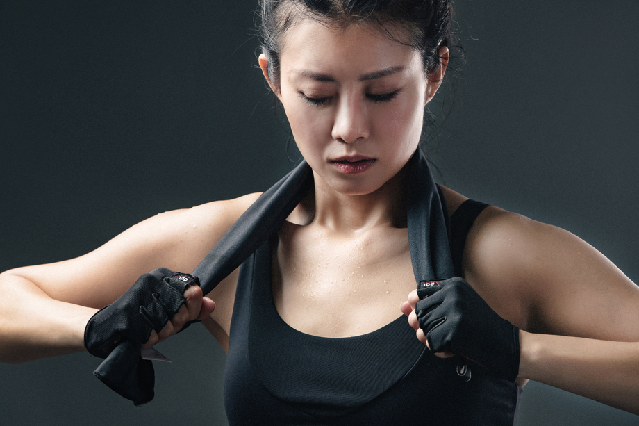 健身完的青年女人拿着毛巾闭着眼睛思考