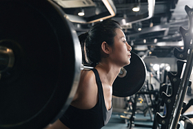 年轻女子在健身房练习抗杠铃