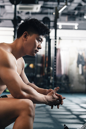 年轻男子在健身房坐着休息照片