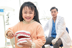 可爱的小女孩和牙科医生照片