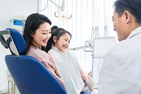 年轻妈妈带着小女孩看牙医照片