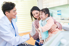 年轻妈妈带着小女孩看牙医图片