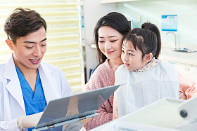 年轻妈妈带着小女孩看牙医图片