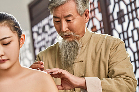 老中医对病人肩膀进行针灸治疗