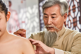 老中医对病人肩膀进行针灸治疗