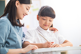老师在指导小学女生学习照片