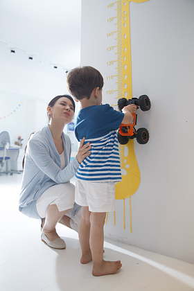青年女人在为小男孩测量身高图片