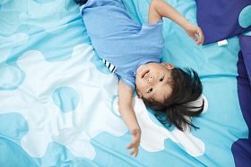 可爱的小男孩在床上玩耍照片