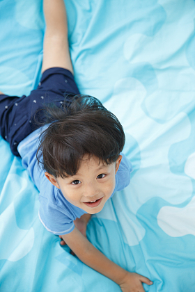 可爱的小男孩在床上玩耍图片