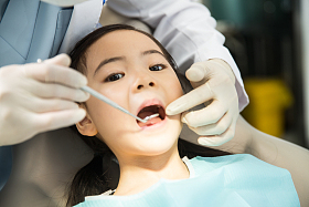 男牙医在为小女孩检查牙齿图片