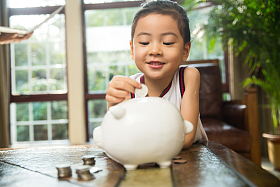 小女孩把钱放入存钱罐图片