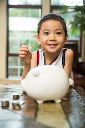 小女孩把钱放入存钱罐图片