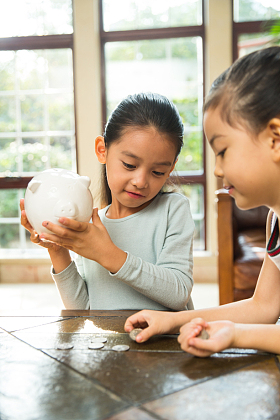 姐妹俩把钱放入存钱罐