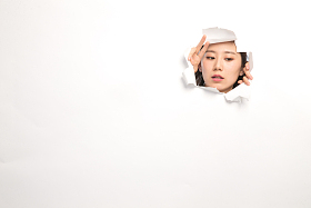 青年女人通过纸洞窥视