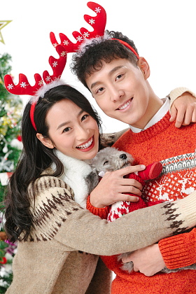 抱着宠物狗的青年情侣过圣诞