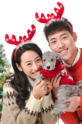 抱着宠物狗的青年情侣过圣诞