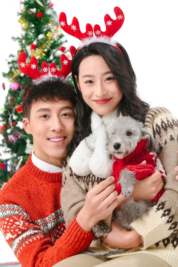 抱着宠物狗的青年情侣过圣诞 抱着宠物狗的青年情侣过圣诞