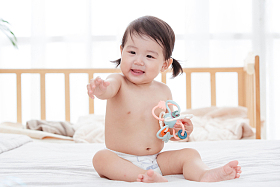 宝宝坐在床上拿着玩具