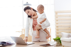 年轻妈妈抱着孩子在家办公图片