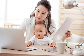 年轻妈妈抱着孩子在家办公