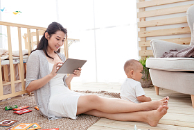 年轻妈妈在家边看孩子边使用电脑