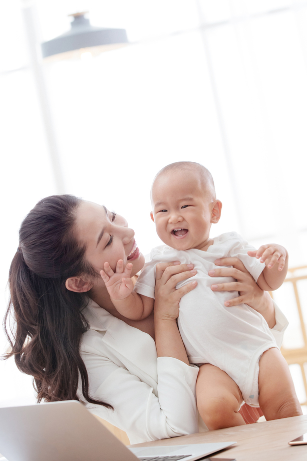 年轻妈妈抱着孩子在家办公 年轻妈妈抱着孩子在家办公