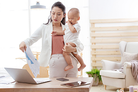 年轻妈妈抱着孩子在家办公图片