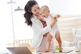 年轻妈妈抱着孩子在家办公图片