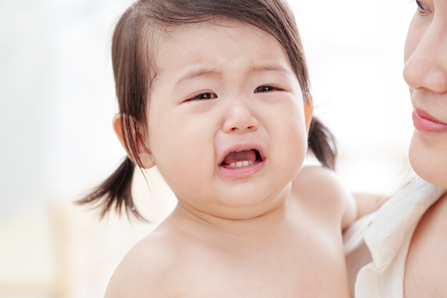 年轻妈妈抱着哭着的宝宝照片