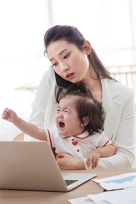 年轻妈妈抱着孩子使用电脑照片