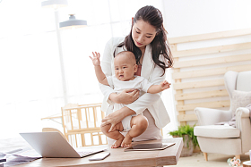 年轻妈妈抱着孩子在家办公