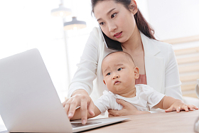 年轻妈妈抱着孩子在家办公图片