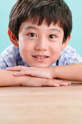 小男孩手托下巴趴在桌子上