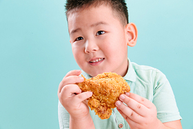 可爱的小男孩吃炸鸡照片