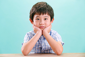 小男孩手托下巴趴在桌子上图片