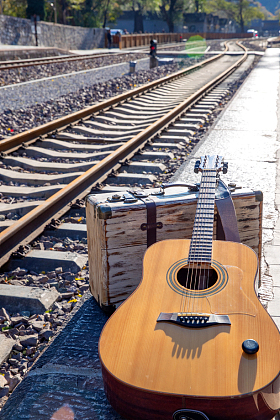 铁轨旁边的吉他和旅行箱图片