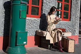 青年女人坐在火车站站台上看书