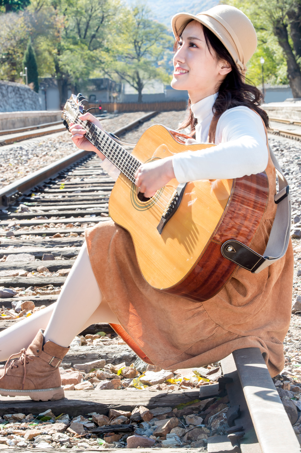 青年女人坐在铁路边弹吉他图片