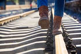 青年女人徒步走在铁轨上