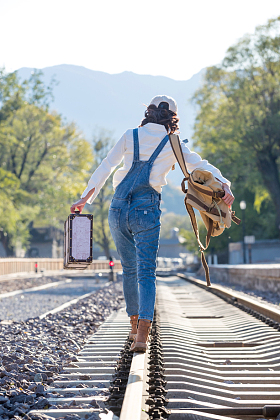 青年女人徒步走在铁轨上