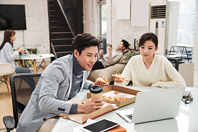 青年商务人士边吃披萨边工作图片