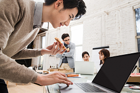 青年商务男士边吃披萨边工作