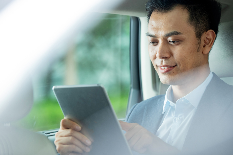 商务男士坐在汽车里使用平板电脑 商务男士坐在汽车里使用平板电脑