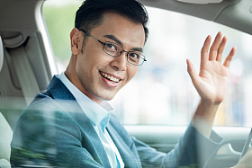 商务男士坐在汽车里打招