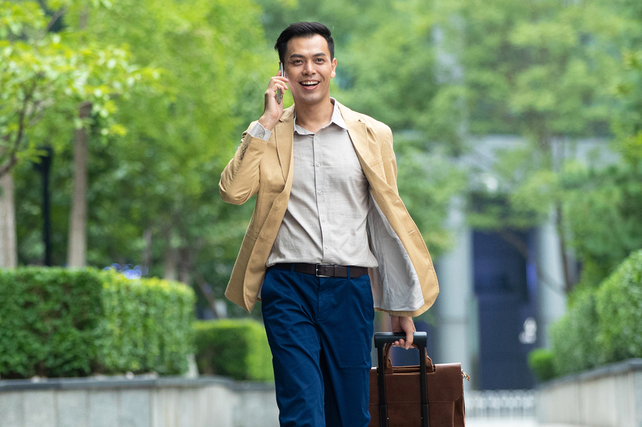 户外拉着行李打电话的商务男子